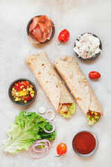 Tortilla wraps sandwiches with fresh various ingredients. Top view, blank space