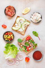 Open wholemeal sandwiches and various ingredients on rustic surface