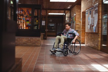 Fototapeta na wymiar Disabled schoolboy on wheelchair in corridor at school