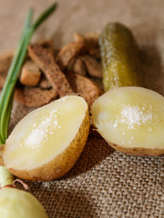 Boiled potatoes in a peel with salt and a green onion on a close-up table. Healthy food.