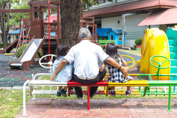 rear view of an elderly with his grandchildren in playground