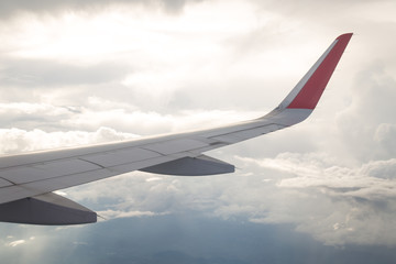 Obraz premium Wing of an airplane flying above the blue sky and clouds.