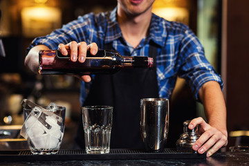 Barman at work,Barman pouring hard spirit into glasses in detail,Bartender is pouring tequila into glass,preparing cocktails,service concept