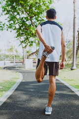 Young man stretching bodies, warming up for jogging in public park. © Touchr
