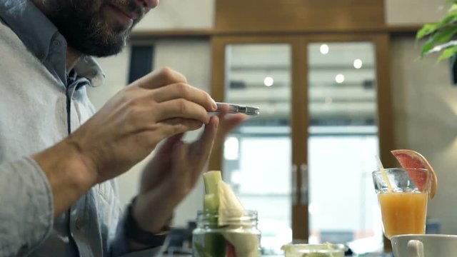 Young Man Taking Photo Of Food And Drink With Cellphone Sitting In Cafe 
