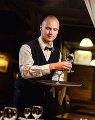 Waiter served table in the restaurant before the feast,Waiter in uniform waiting an order,Waiter with a white towel on his hand,Confident waiter