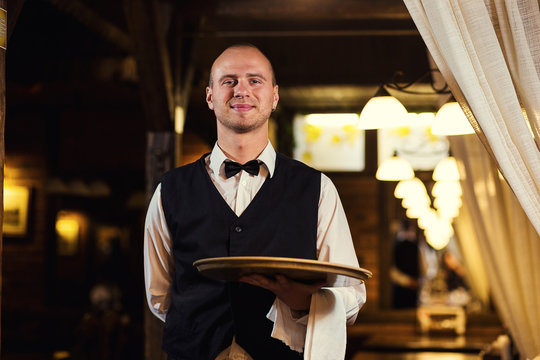 Waiter with a tray in his hand,Waiter in uniform waiting an order,Confident waiter