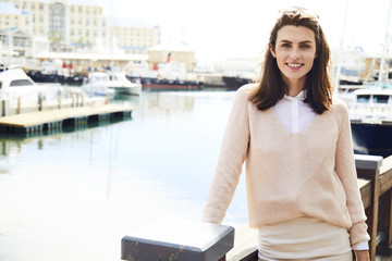 Fototapeta premium Beautiful brunette standing at harbor, portrait