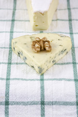 Cheese roquefort and brie with one walnut are on the towel