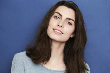 Fototapeta premium Gorgeous green eyed woman in blue studio, smiling