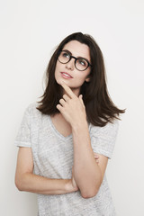 Brunette woman in glasses thinking, studio