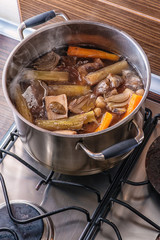 traditional beef broth with vegetable, bones and ingredients in pot, cooking recipe