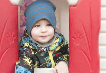 Happy boy peeking out of a toy house , close-up , portrait
