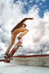 A young skateboarder makes Wallie in a skatepark, jumping on a skateboard into the air with a coup © yanik88