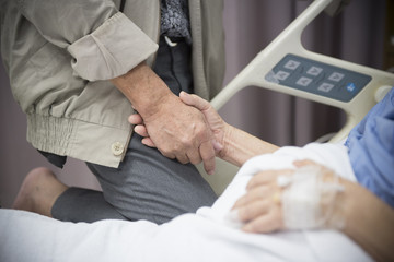 An old women Sick patient lying on bed holding her husband hand in hospital for medical background
