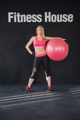 Young attractive slim woman in sportswear, doing fitness exercise ball.