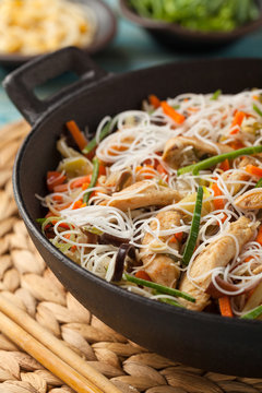 Rice noodles with chicken, mushrooms mun and vegetables in wook.