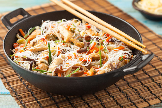 Rice noodles with chicken, mushrooms mun and vegetables in wook.