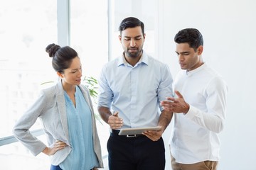 Business colleagues discussing over digital tablet in office