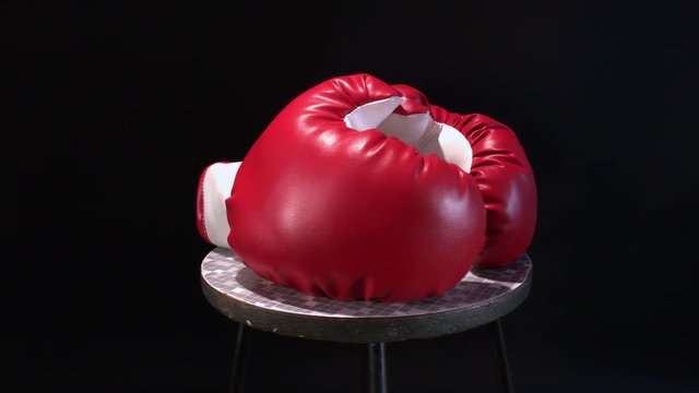 Red boxing gloves rotating on round stool.
