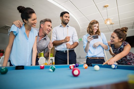 Smiling business colleagues playing pool