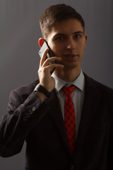 Young man in suit is speaking on the sell phone