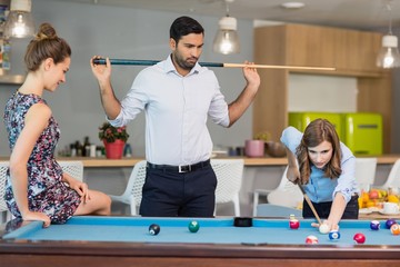 Business colleagues playing pool in office space