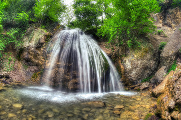 Fototapeta premium Beautiful waterfall on the mountain river with green trees.