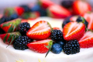 A slide of berries: strawberries, blueberries and blackberries are decorated with a cake