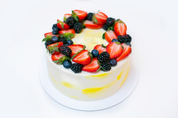 Festive lemon cake with strawberries, blueberries and blackberries on white background