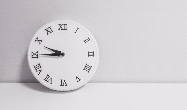 Closeup white clock for decorate show a quarter to ten o'clock or 9:45 a.m. on white wood desk and wallpaper textured background in black and white tone with copy space