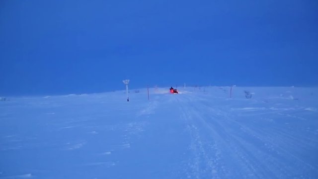 Man rides sidecar motorcycle on snowed and frozen road during dawn in Norway. There is little sideway skidding.