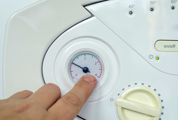 Man adjusting the water temperature on a heating boiler for household radiators