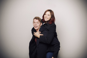 Happy young couple in winter clothes having fun in studio over white background