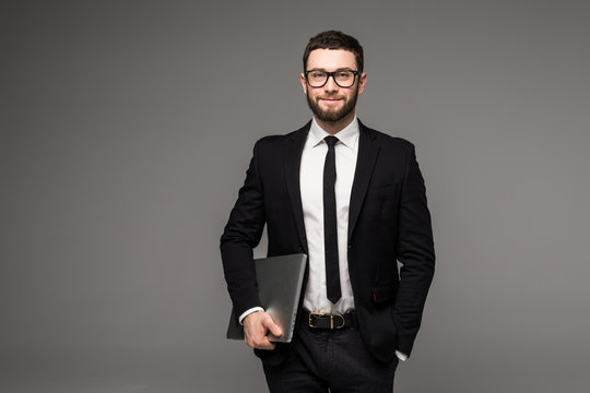 Handsome business man in glasses and suit holding laptop in hands side view isolated gray background