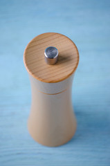 wooden grinder for salt on blue background, vertical