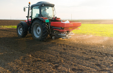 Naklejka premium Tractor spreading artificial fertilizers
