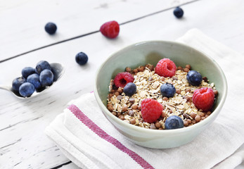 Delicious cereal breakfast with bowl and fresh fruits. Fresh blueberry and raspberry fruits, healthy eating scene.