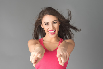 Portrait of a happy young female pointing towards camera