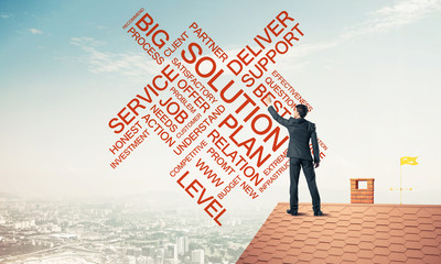 Young businessman standing on house roof and writing leadership 