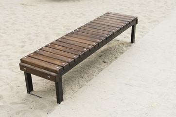 Wooden brown bench on sand.
