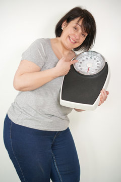 Overweight woman holding scale on white background