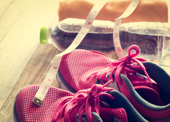 Sneakers, towel, water and tape measure on wooden floor