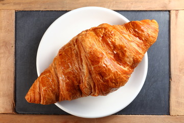 The fresh croissant put on the white dish represent the pastry and food concept related idea.