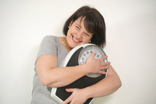 Overweight woman holding scale on white background