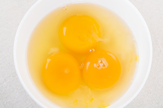 Egg yolk in white bowl on table, top view