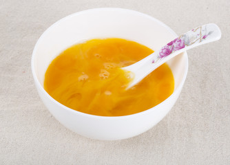 Egg yolk in white bowl on table, closeup