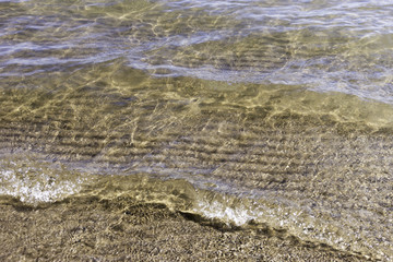 Fresh water lapping on clean sandy beach, closeup background with space