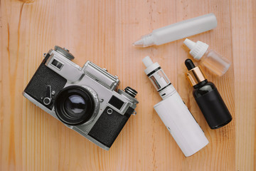 Modern electronic mech mod vaping device. Electronic cigarette and photo camera on a wooden...