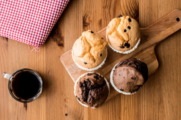 Chocolate and Vanilla Muffins with coffee on wooden surface.